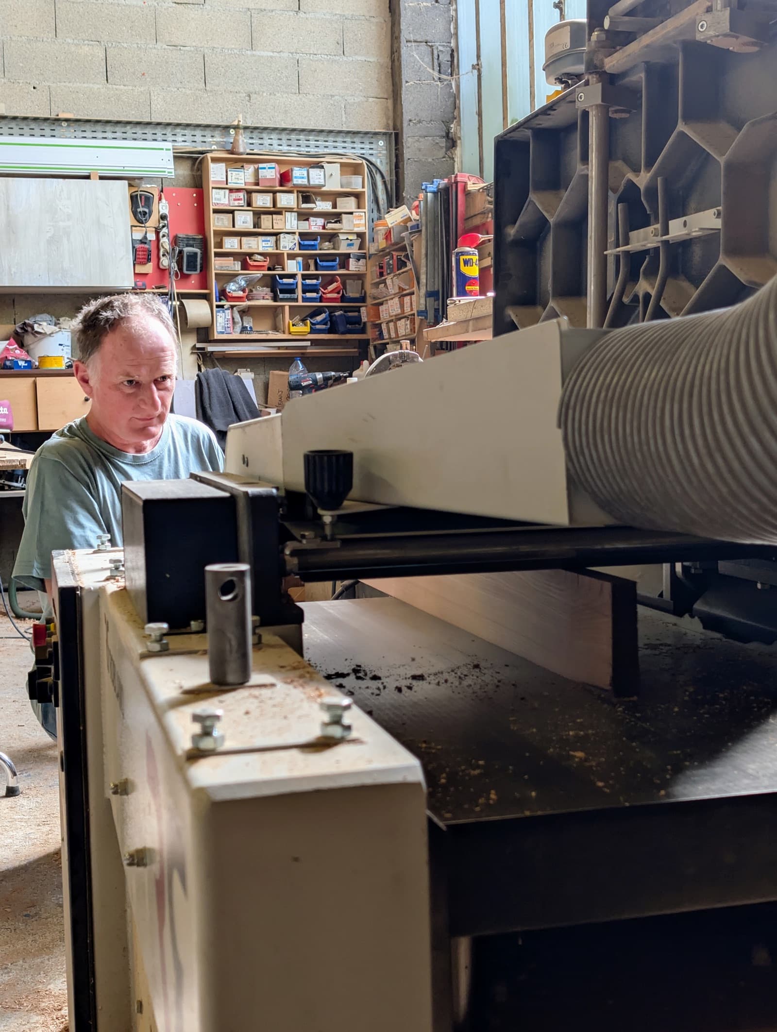 Le menuisier passant une planche à la raboteuse dans l'atelier