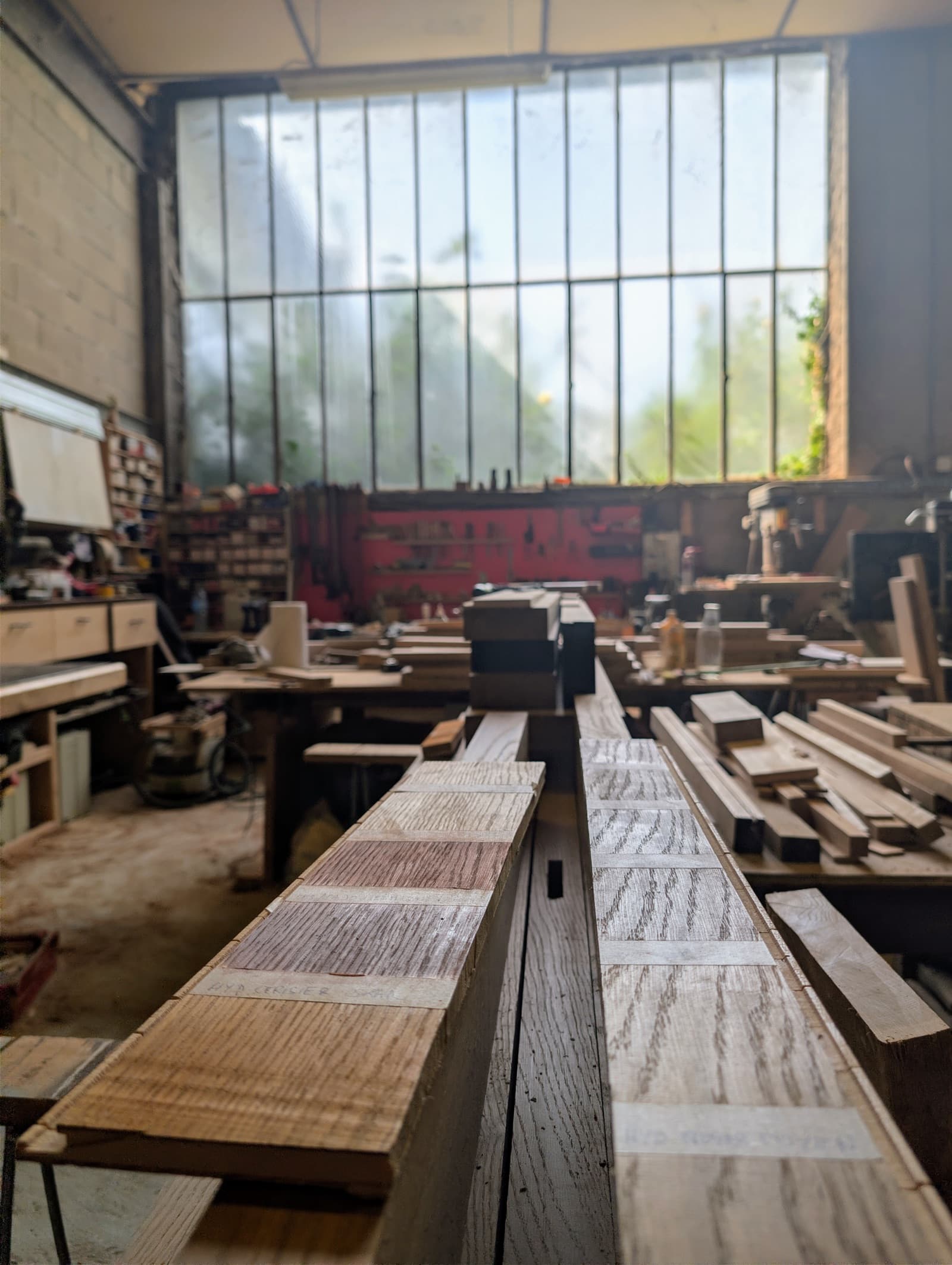 Échantillon des différentes essences de bois au premier plan de l'atelier de Chaneins, sous la verrière